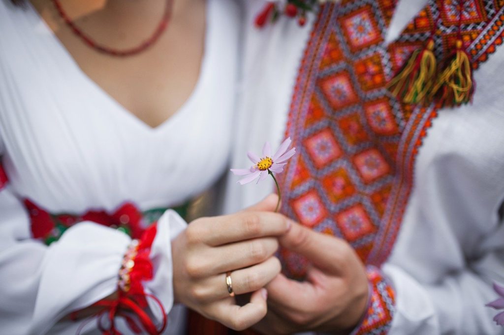 Marriage. Man and woman in traditional clothing, holding a flower.