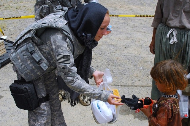 focus groups examples Anthropology. Image of a woman soldier giving a toy to a young child.