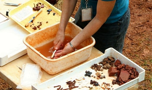 Archaeology. Image of a person scrubbing artifacts that were excavated.
