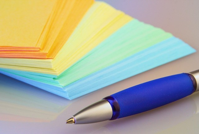 Free listing. A stack of paper in different colors, with a blue pen.