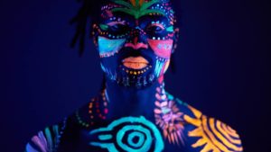 A person with glow in the dark paint on their face and body